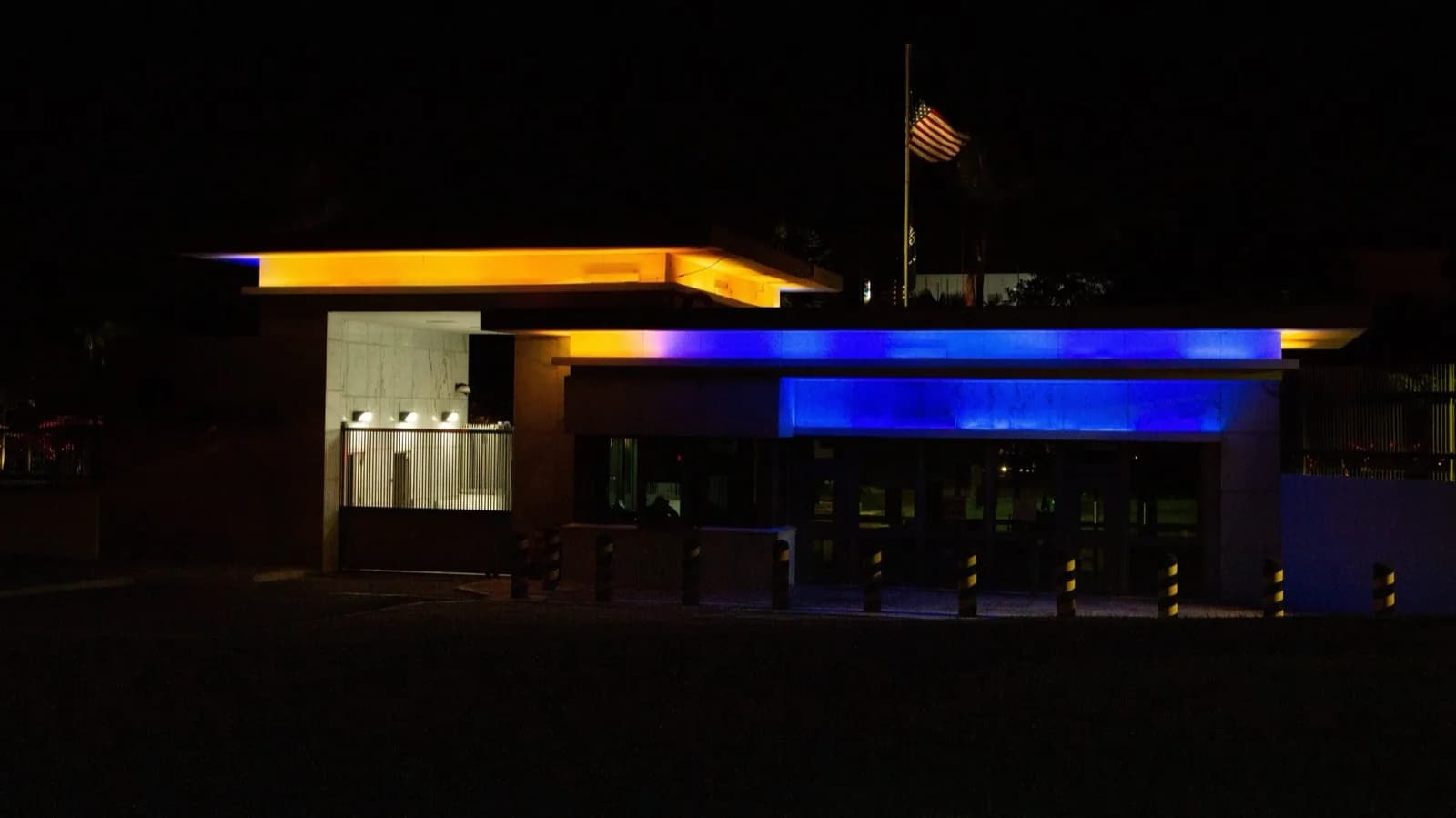 Portaria da Embaixada dos Estados Unidos em Brasília à noite, com a bandeira americana hasteada