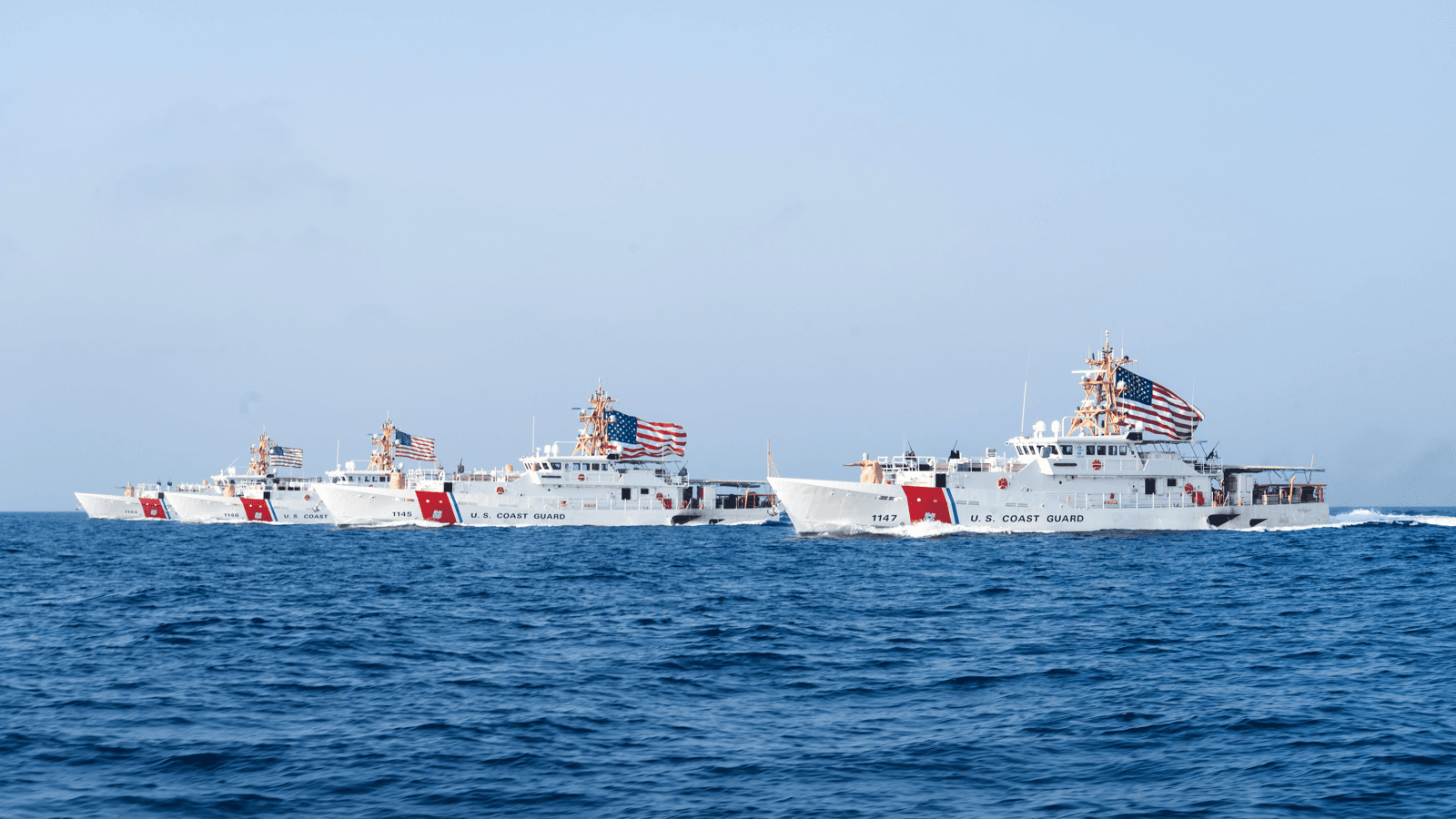 Quatro navios-patrulha da Guarda Costeira dos Estados Unidos navegam lado a lado no Estreito de Ormuz, com bandeiras americanas hasteadas (imagem de arquivo, 2022)