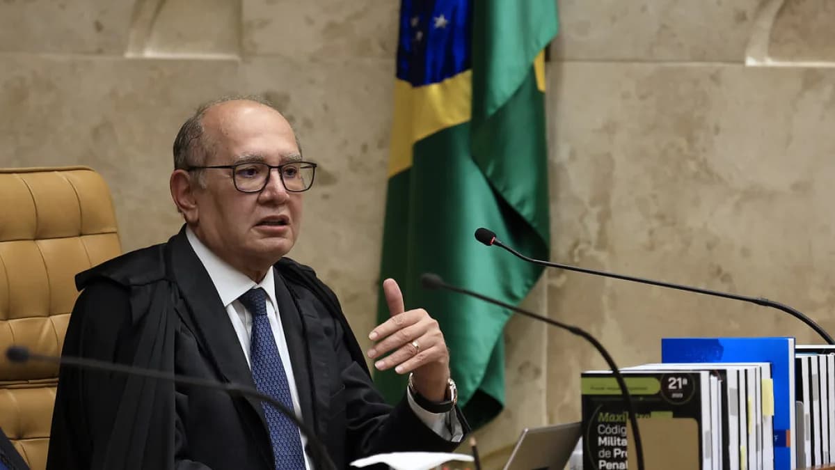 Ministro Gilmar Mendes fala durante sessão plenária do STF, vestindo toga, com a bancada e a bandeira do Brasil ao fundo