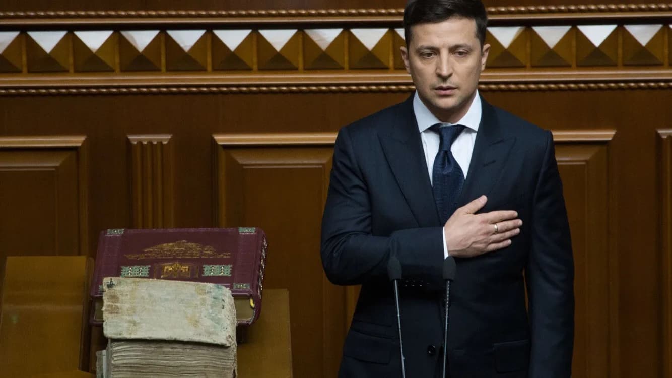 Volodymyr Zelensky em pronunciamento no Parlamento ucraniano, de terno escuro, com a mão no peito