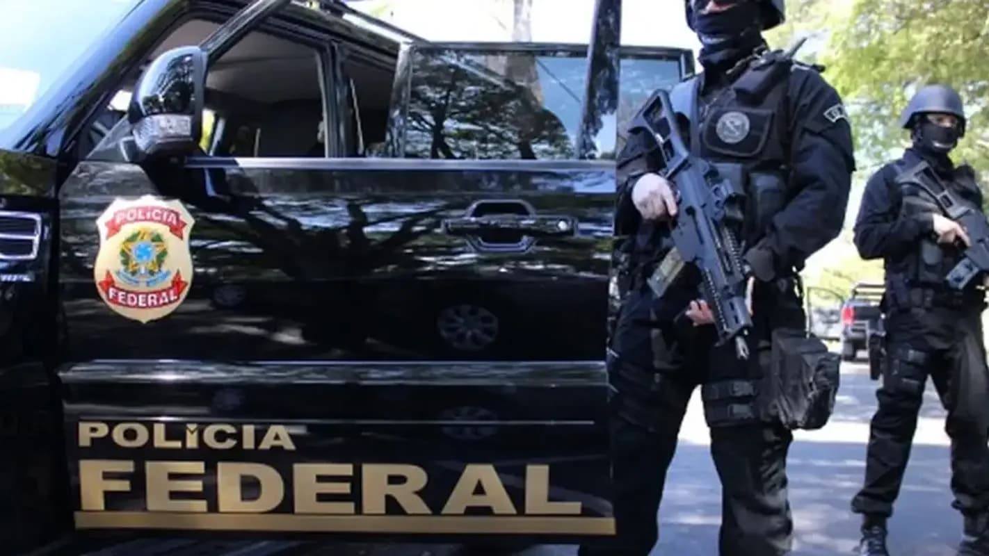 Agentes armados da Polícia Federal ao lado de viatura durante operação, em imagem de arquivo