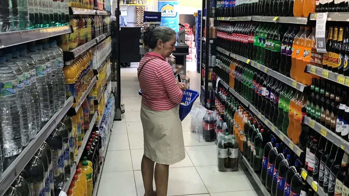 Mulher observa rótulos de produtos nas prateleiras de um supermercado