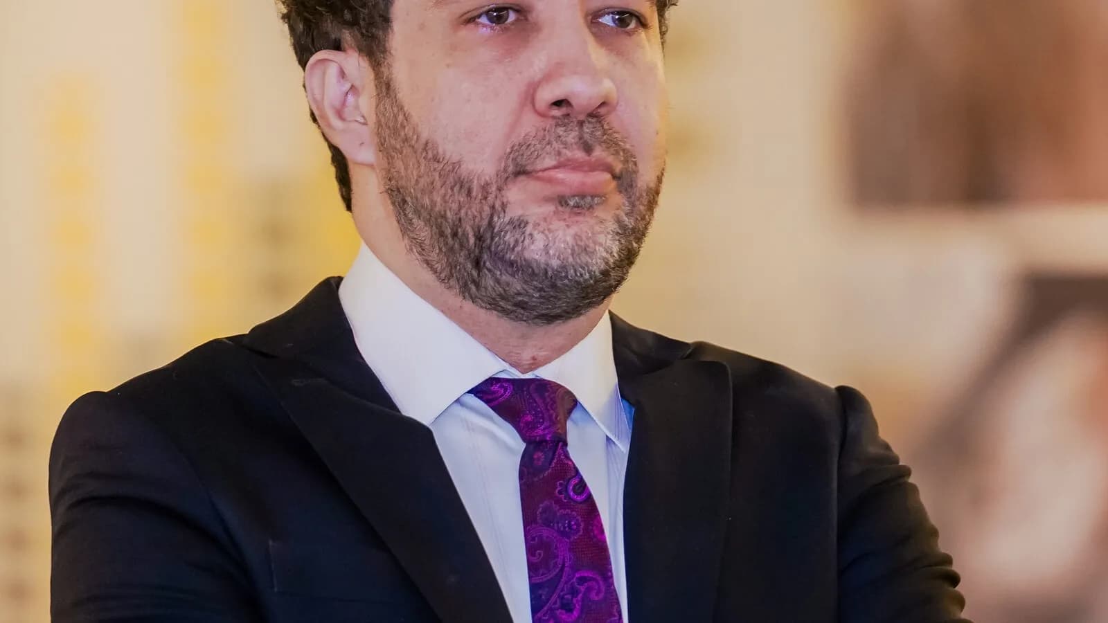 André Janones, de terno escuro e gravata estampada, posa de braços cruzados