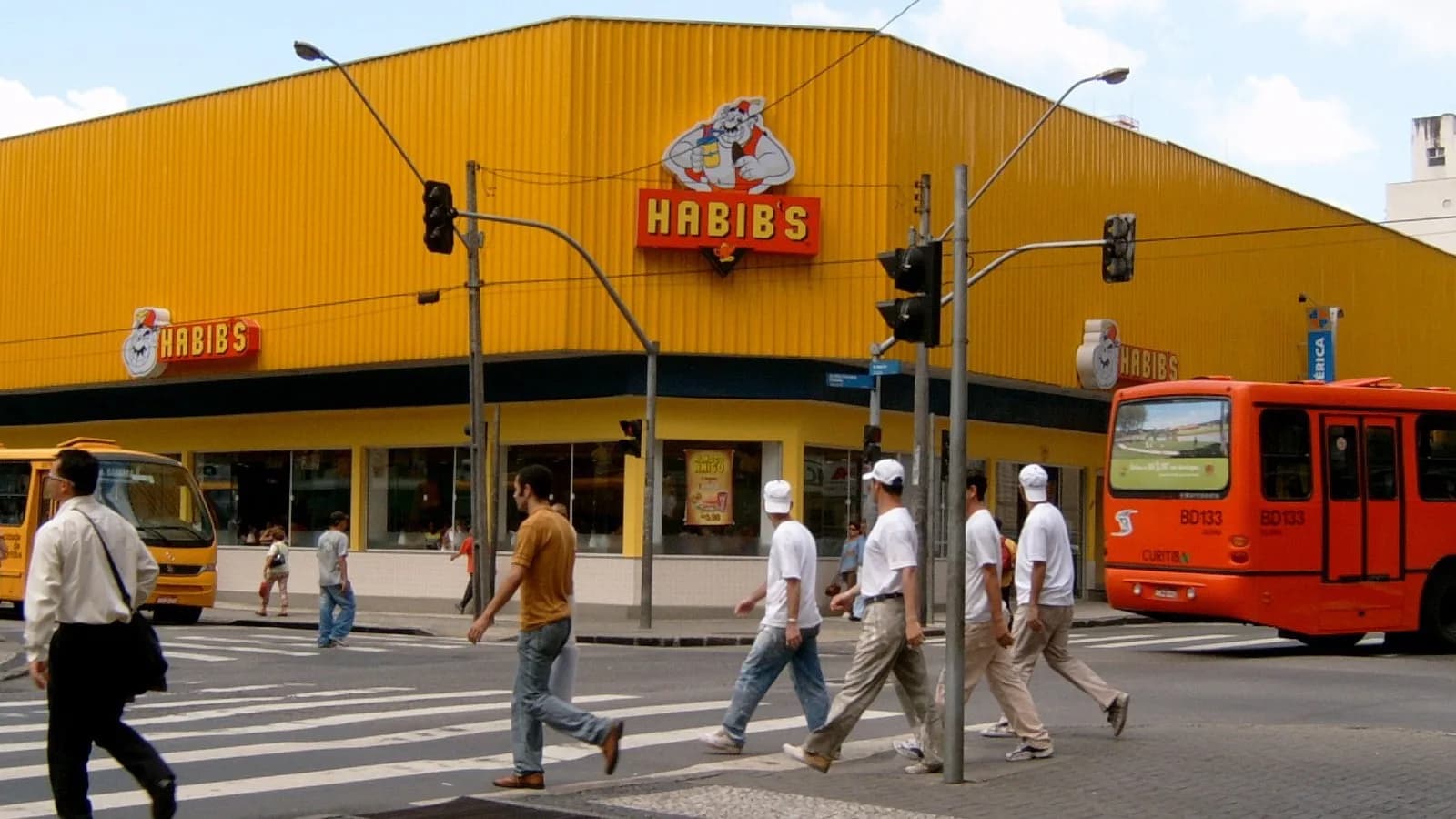 Fachada de uma unidade do Habib's, com pedestres atravessando a rua em frente à loja (imagem de arquivo)