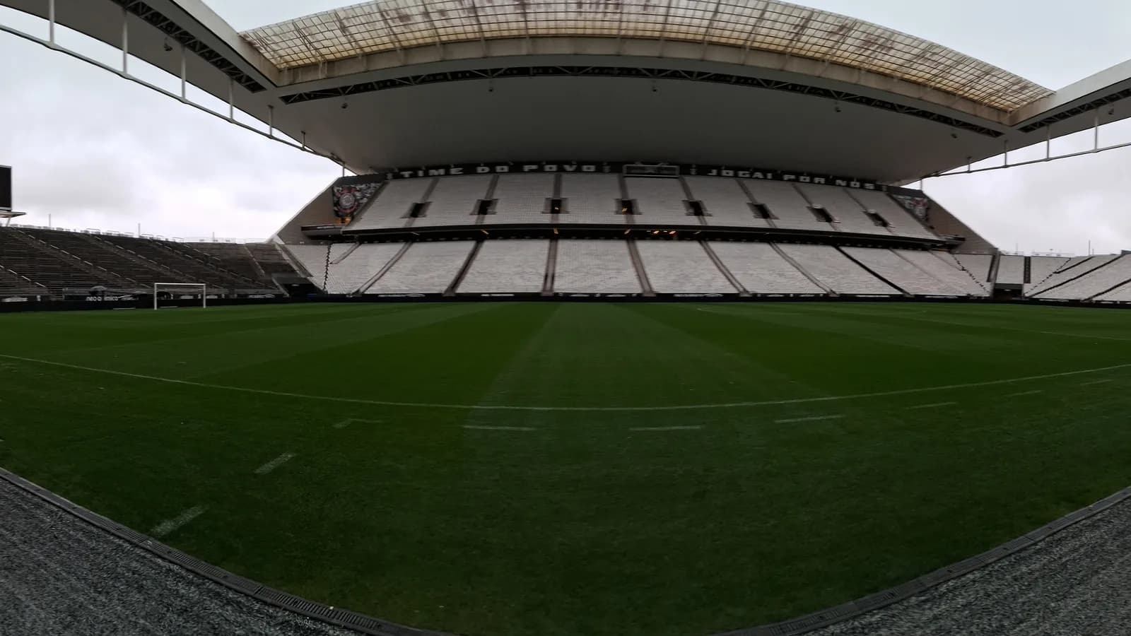 Vista interna da Neo Química Arena, estádio do Corinthians, com o gramado e a arquibancada ao fundo