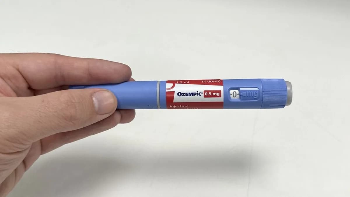 Mão segurando uma caneta injetável de Ozempic (semaglutida), medicamento da classe GLP-1 usado no tratamento de diabetes e obesidade