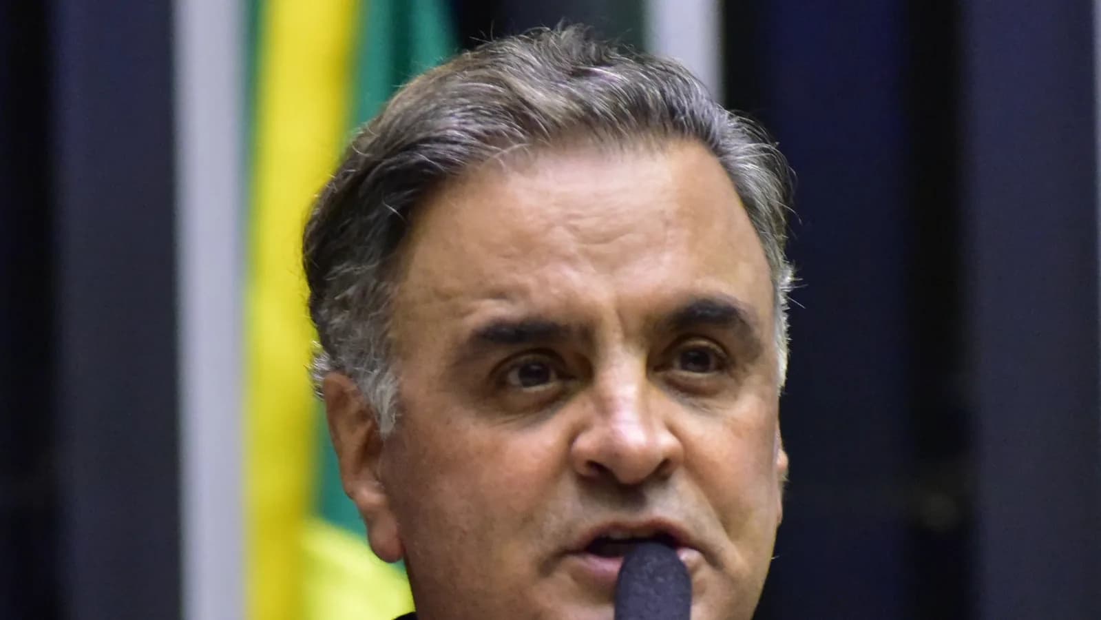 Aécio Neves discursa em plenário da Câmara dos Deputados, com bandeira do Brasil ao fundo