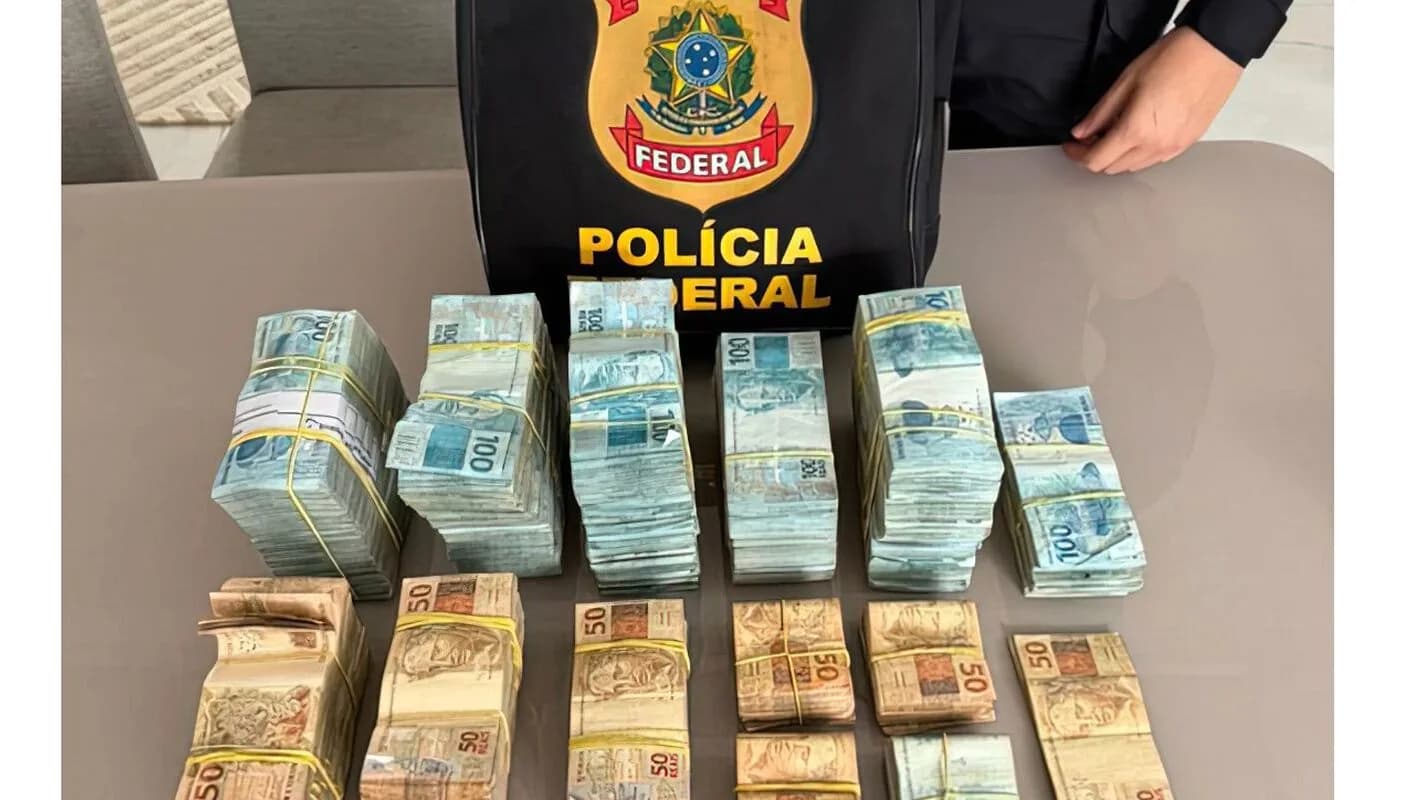 Maços de dinheiro apreendidos ao lado de bolsa com o brasão da Polícia Federal, em foto de arquivo
