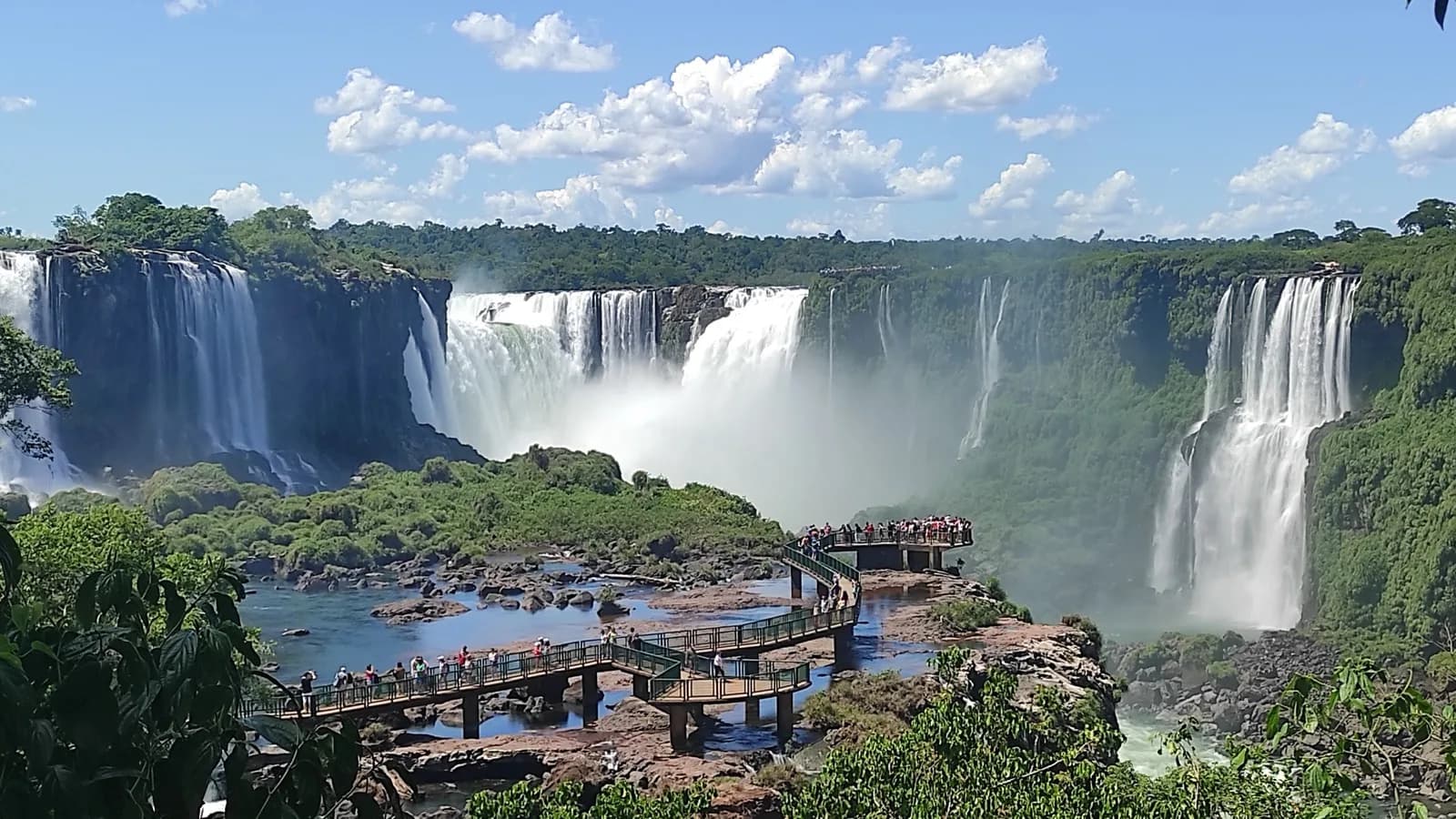 Vista das Cataratas do Iguaçu com passarela cheia de turistas em primeiro plano, foto de arquivo