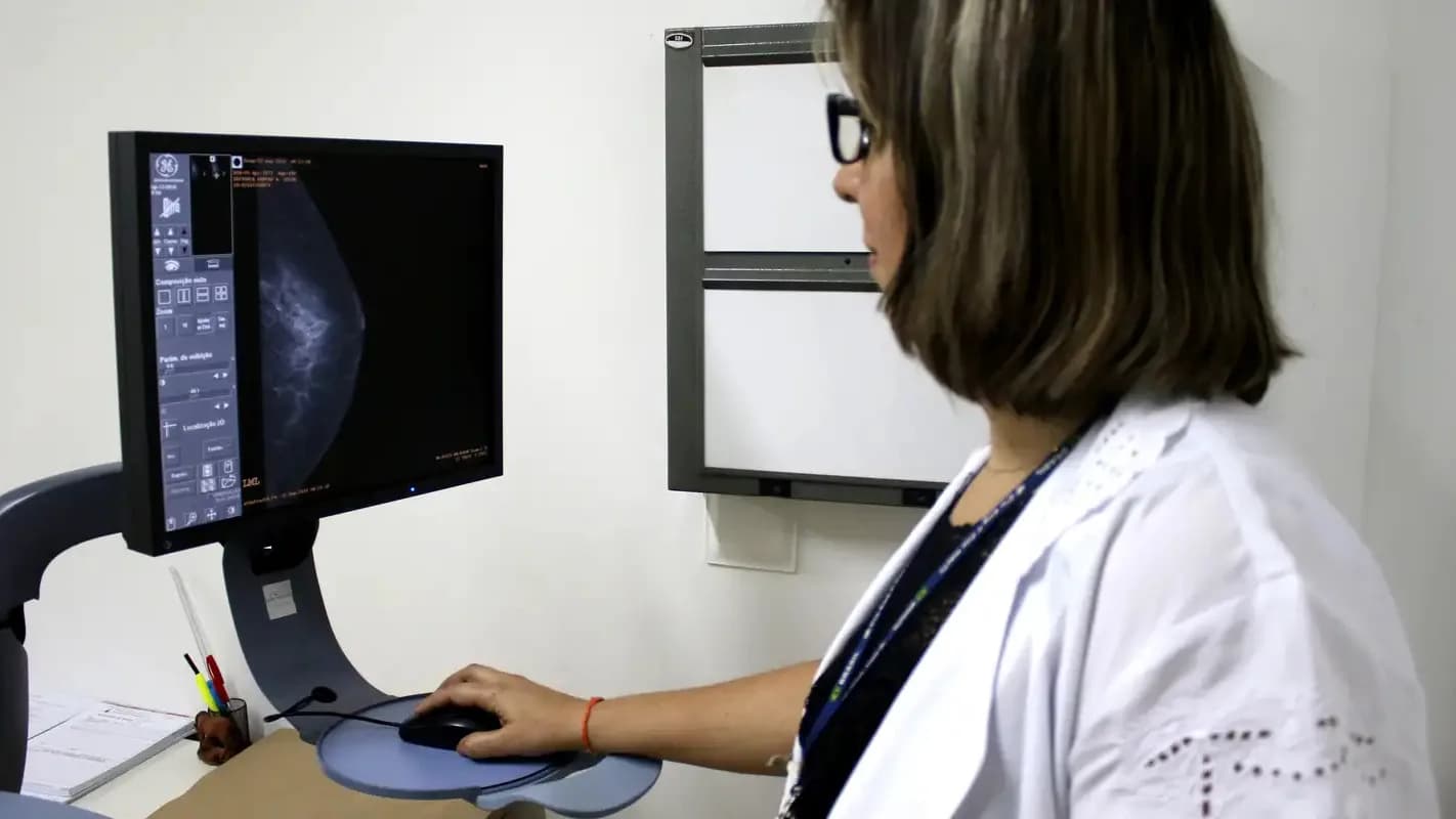 Profissional de saúde analisa imagem de mamografia em consultório