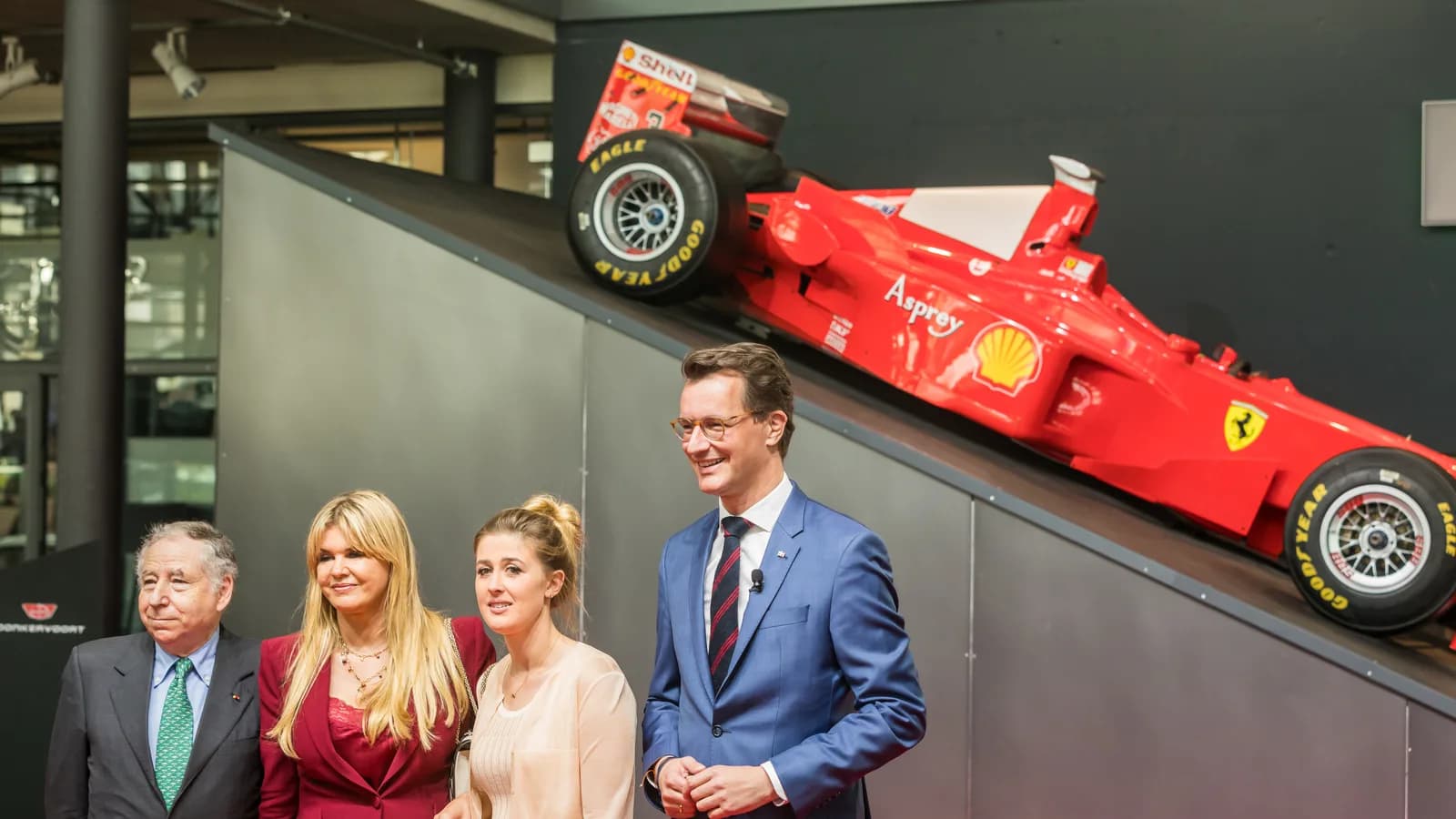 Corinna Schumacher e a filha Gina Maria em cerimônia de premiação a Michael Schumacher, com carro de Fórmula 1 ao fundo