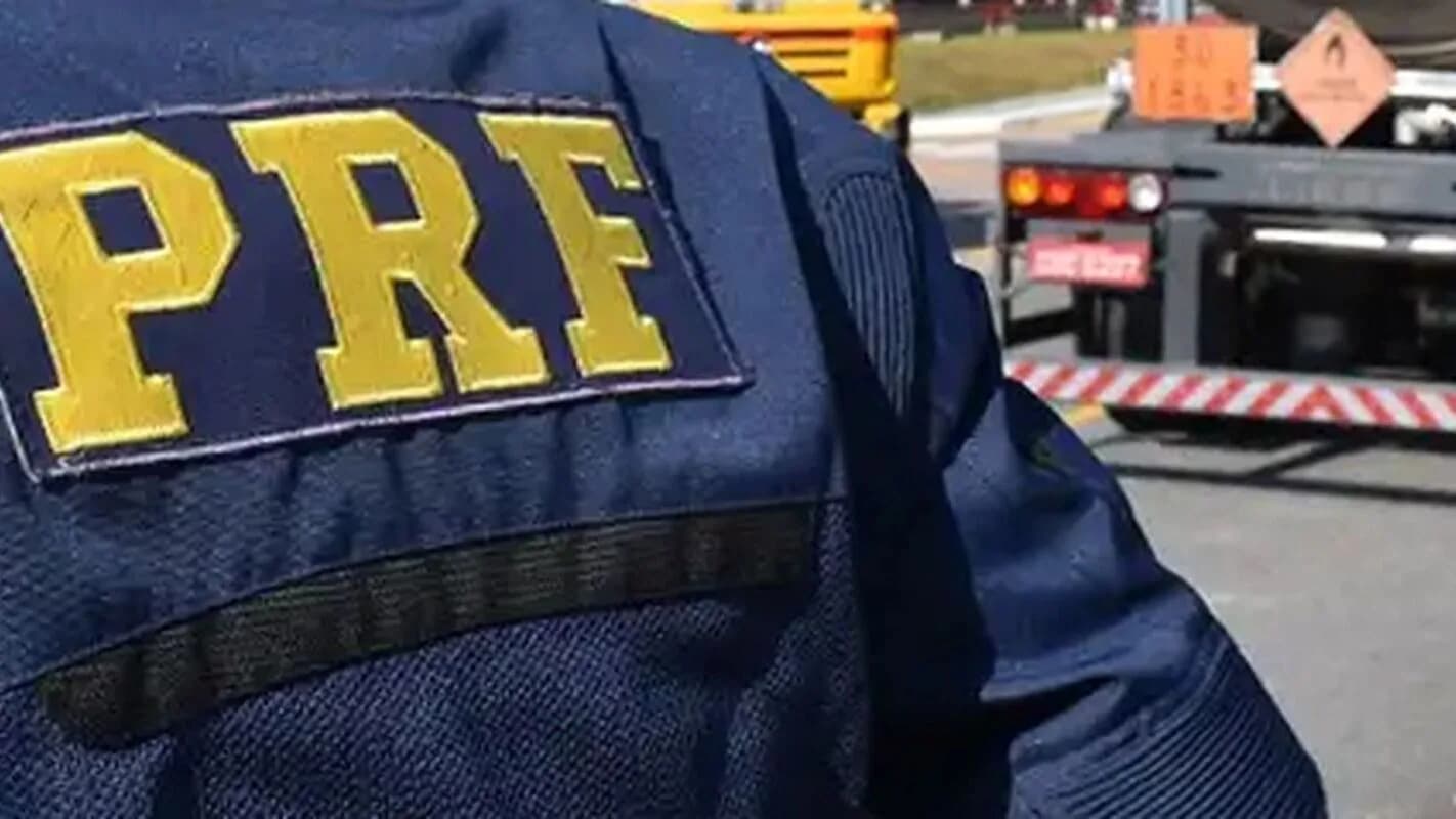 Agente da Polícia Rodoviária Federal com a sigla PRF nas costas do uniforme, durante fiscalização em rodovia