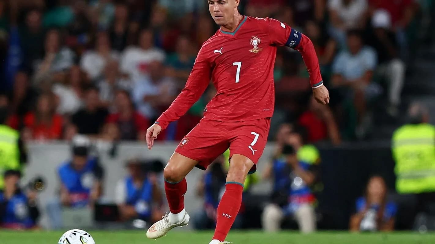 Cristiano Ronaldo, de uniforme vermelho da seleção portuguesa, conduz a bola em campo