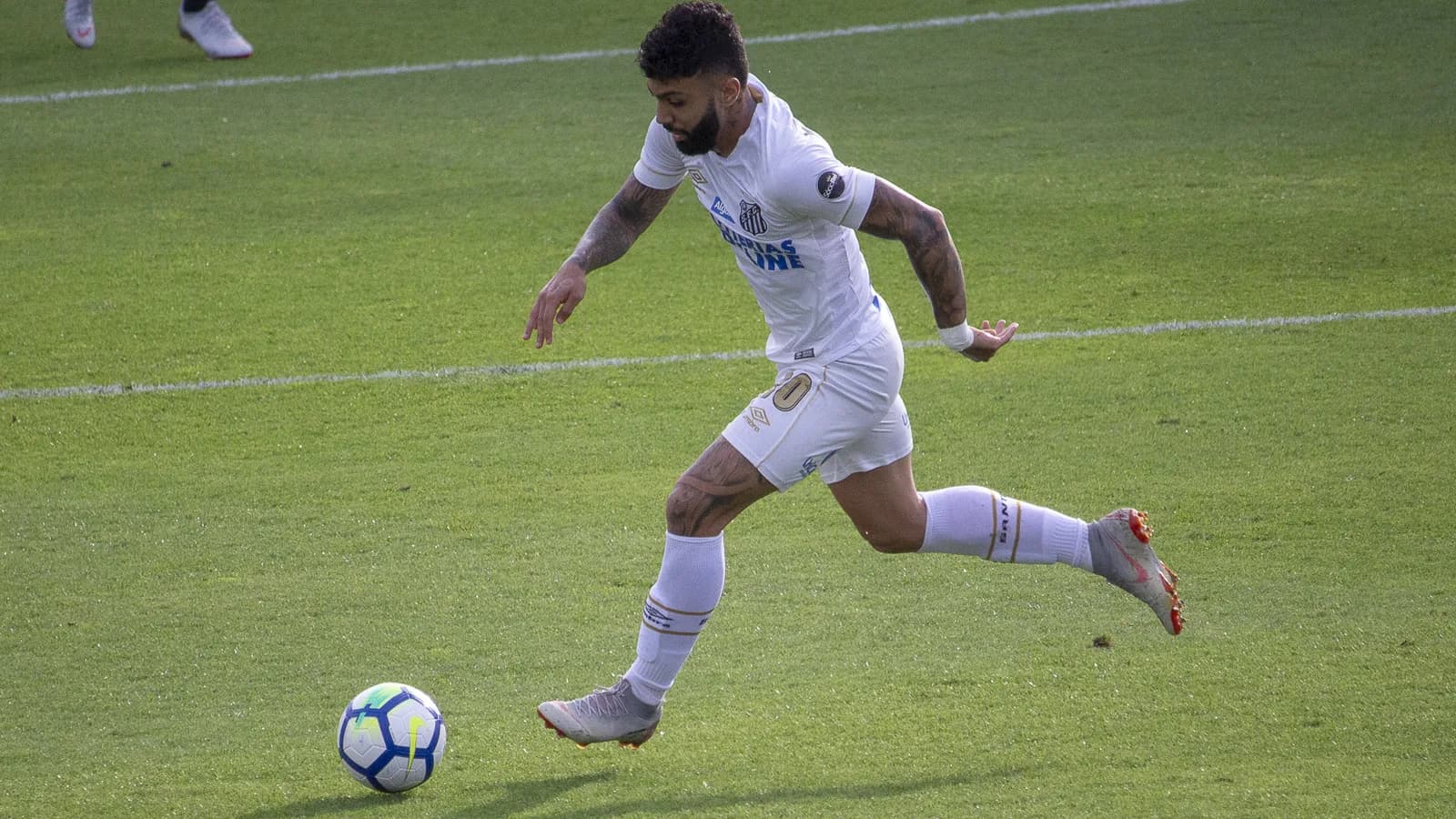 Gabigol, atacante do Santos, conduz a bola durante partida, uniforme branco