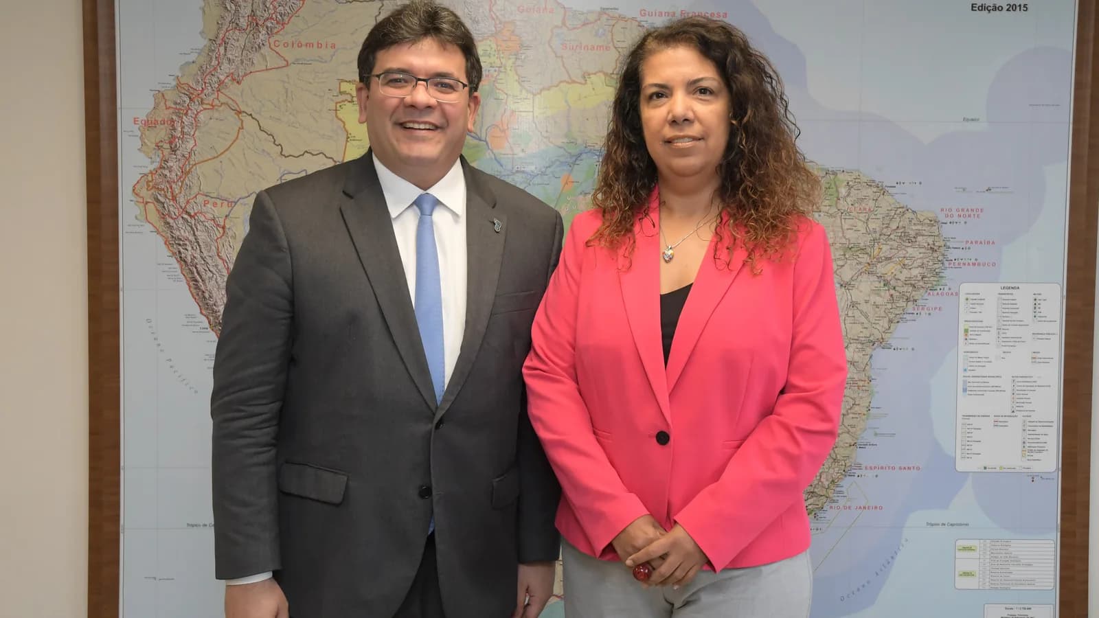 Governador do Piauí Rafael Fonteles em pé, ao lado de outra pessoa, diante de mapa do Brasil